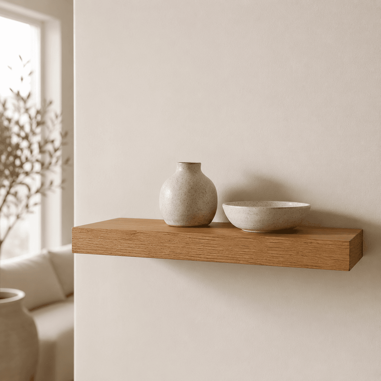 A single floating oak wall shelf mounted on an off-white wall holding two small objects
